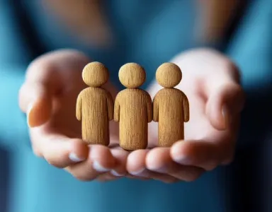 Hands holding wooden figures, symbolizing community or care.