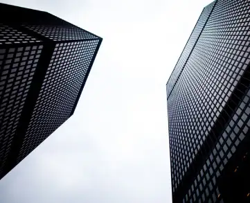 Upward view of two modern skyscrapers against a cloudy sky.