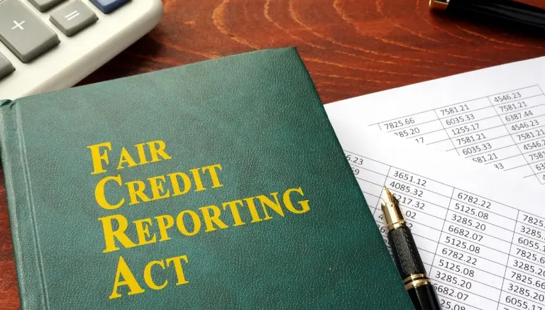 A book titled "Fair Credit Reporting Act" on a desk next to a pen and financial documents.