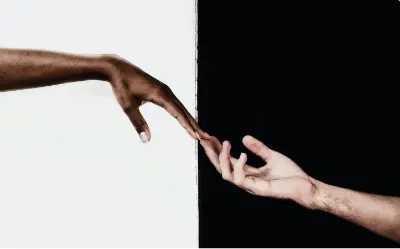Two hands reaching out to each other against a black and white background.
