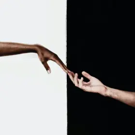Two hands reaching out to each other against a black and white background.